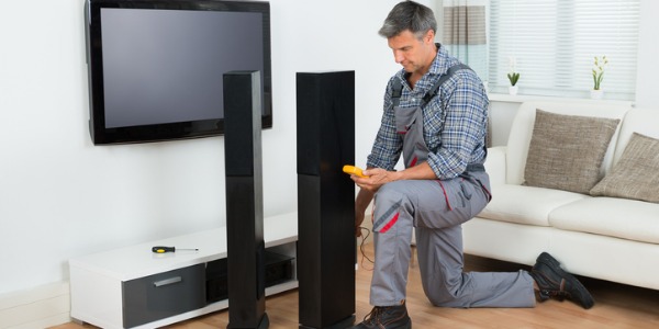 An audio and video equipment technician installing a speaker system in a client's home.