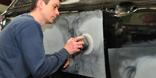 An auto body repairer restoring a damaged car.