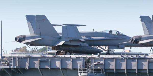 Aircraft launch and recovery specialist helping pilot to land their aircraft on the aircraft carrier deck.