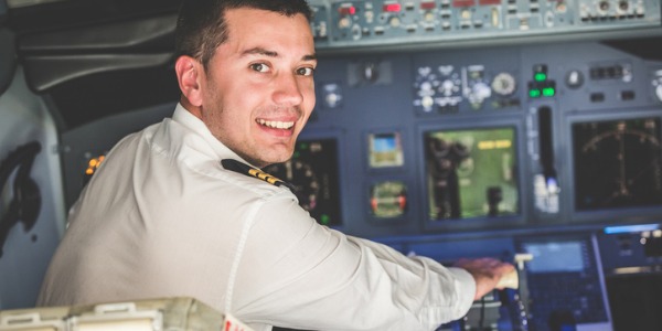A smiling pilot sitting in the cockpit of an airplane.