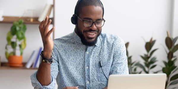 en Customer success manager sitter vid ett skrivbord och pratar med en kund från sin dator.