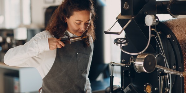 A coffee roaster smelling a sample of coffee beans from the roaster.
