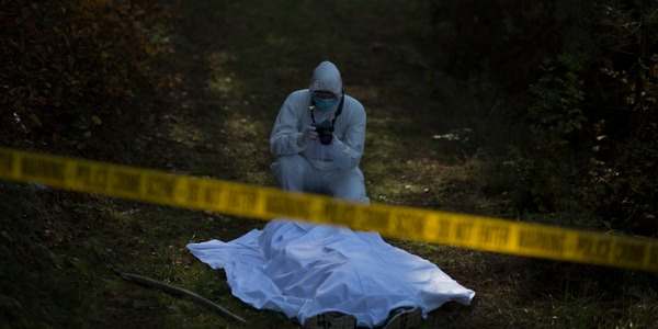 A forensic scientist at the scene of the crime, taking photographs of a corpse.