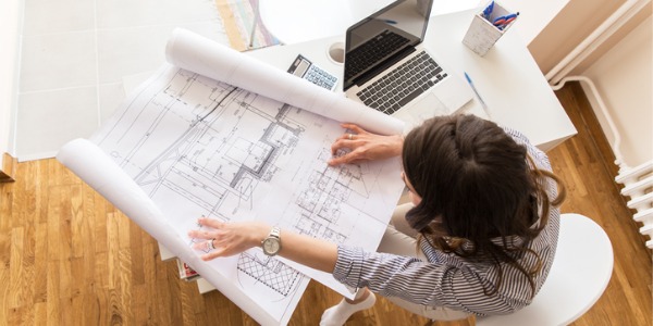 An interior architect sitting at her desk and looking at drawings.