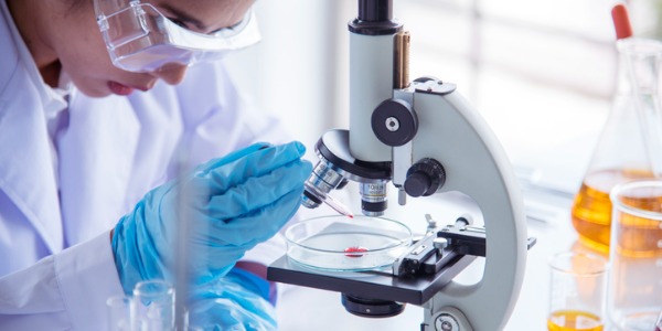 A cellular biologist looking through the microscope.
