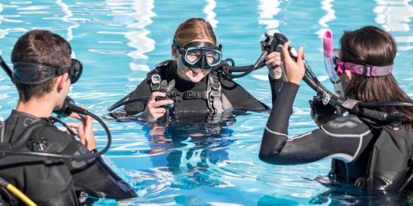 Scuba diving instructor in the pool with two students.