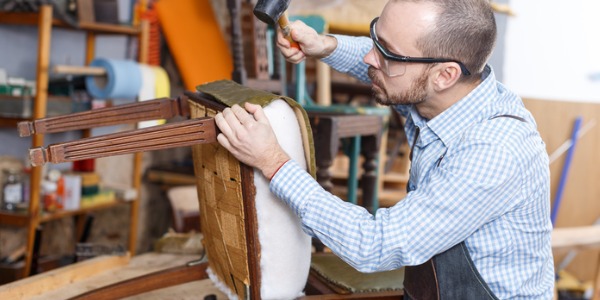 An upholsterer reupholstering a chair.