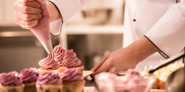 A pastry chef frosting cupcakes.