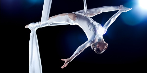 An aerialist up in the air using silks.