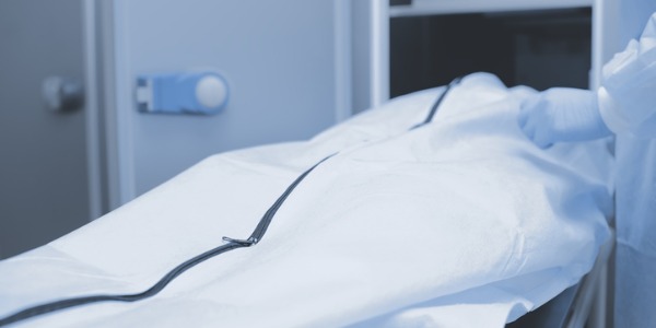 A covered body being prepared for an autopsy.
