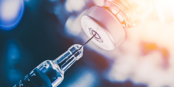 An image of a needle and a syringe, signifying a vaccine shot.