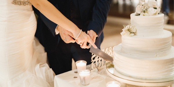 The bride and groom cutting a piece of wedding cake together.