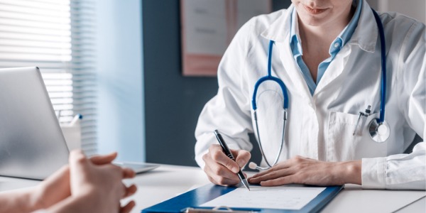 A nurse practitioner sitting at her desk, completing paperwork for a patient.