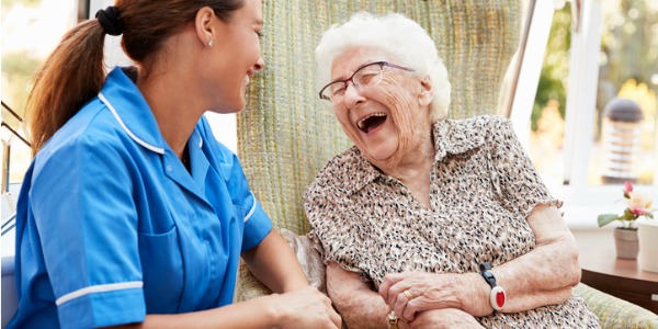 A geriatric nurse laughing with one of her elderly patients.