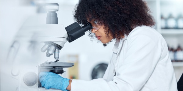 A female biochemist in a lab using a microscope.