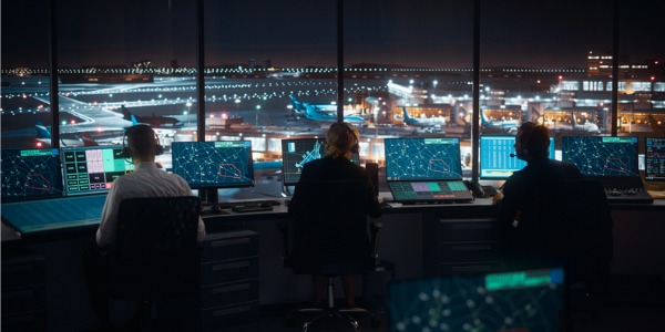 Air traffic controllers working in a control tower, directing aircrafts safely through their assigned flight paths.