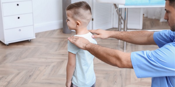A pediatric chiropractor taking a look at a young patient's back.