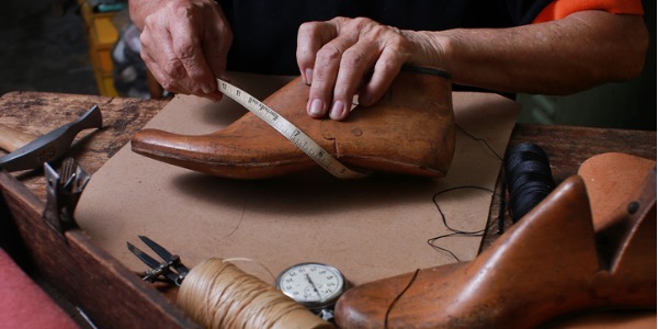 A bespoke shoemaker making a custom pair of shoes for a client.