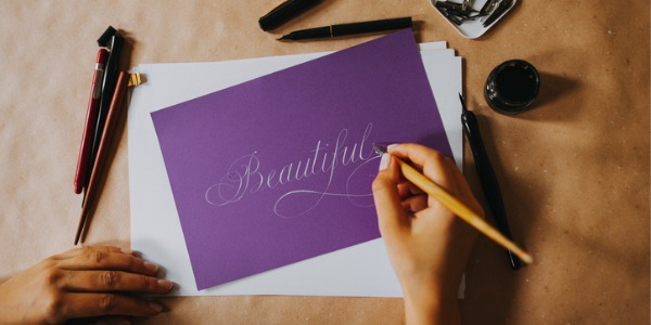 A calligrapher writing the word 'beautiful' in decorative handwriting.