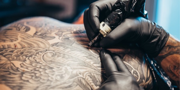 A tattoo artist tattooing his client.