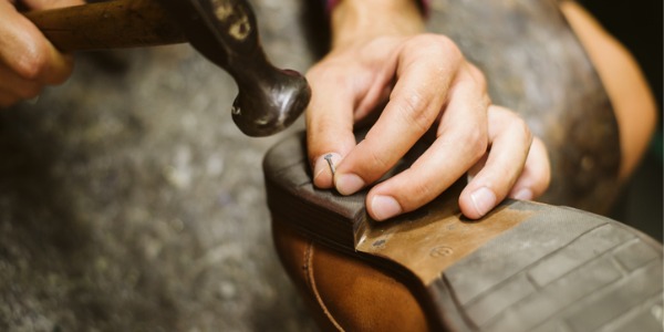A repair shoemaker repairing a used pair of shoes.