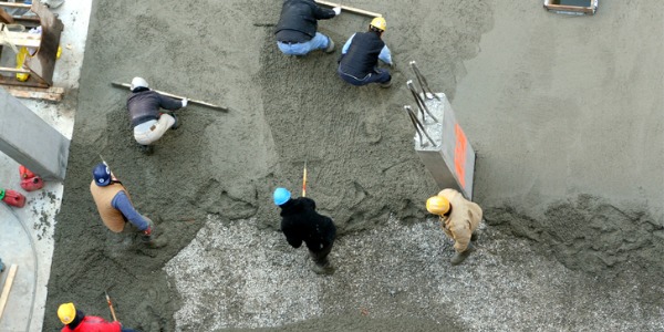 Concrete workers spreading concrete.