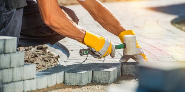 A paving stone installer laying out pavers on a driveway.