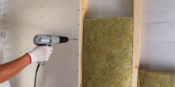 A drywall installer installing drywall panels.