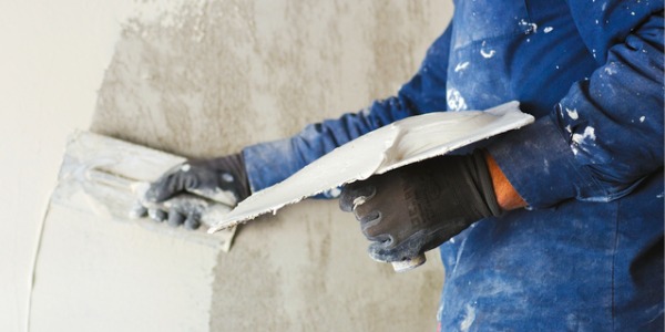 A plasterer applying a coat of plaster to a wall.