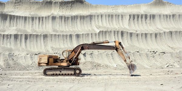 An extraction worker working an excavator in a mine.