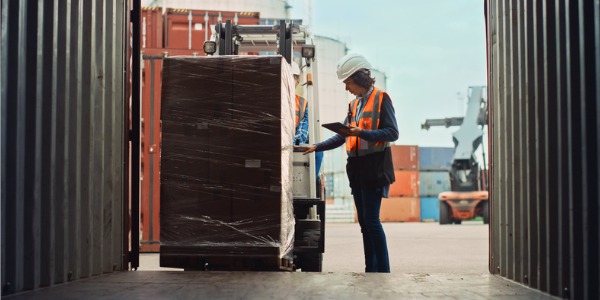 A freight and cargo inspector outside inspecting a shipment.