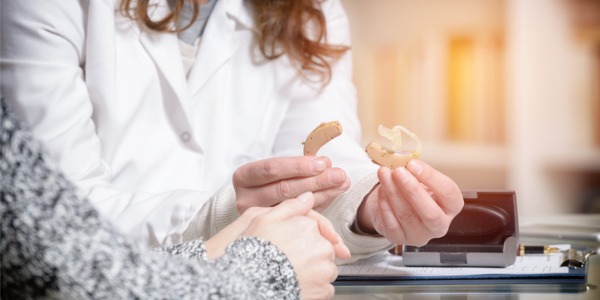 A hearing aid specialist showing a patient a type of hearing aid.