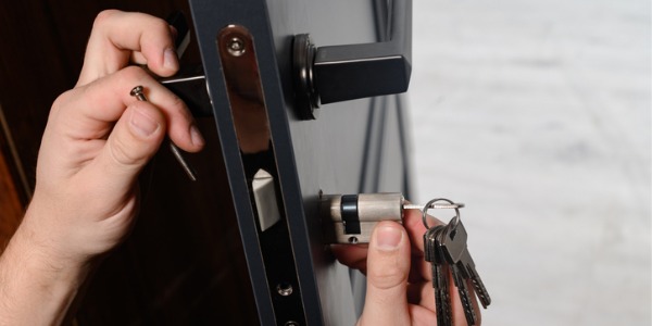 A locksmiths installing a lock on a door.
