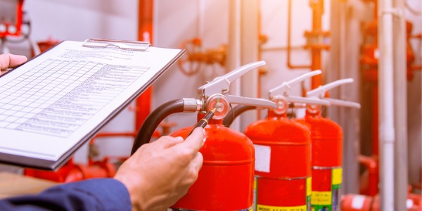 A fire inspector checking fire extinguishing equipment in an industrial facility.