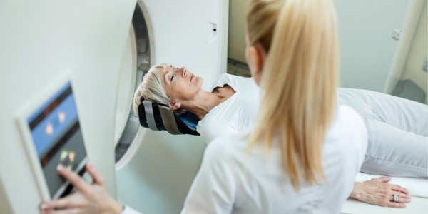 An MRI technologist operating a magnetic imaging machine with a patient.