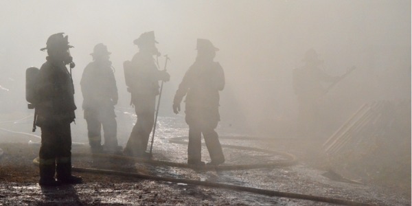 Silhouettes of military firefighters through the smoke.