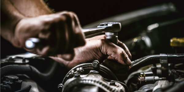 Close up of a mechanic's hands holding a wrench and fixing a mechanical system.