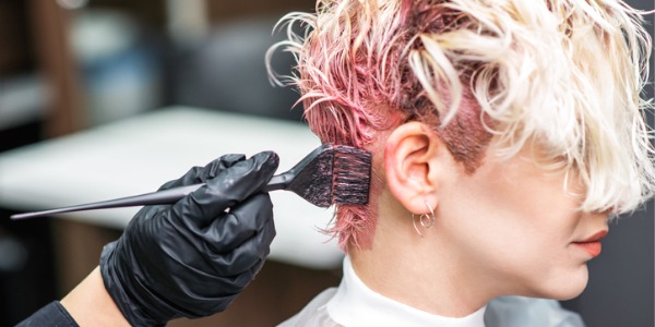 A hair colorist dyeing a client's hair.