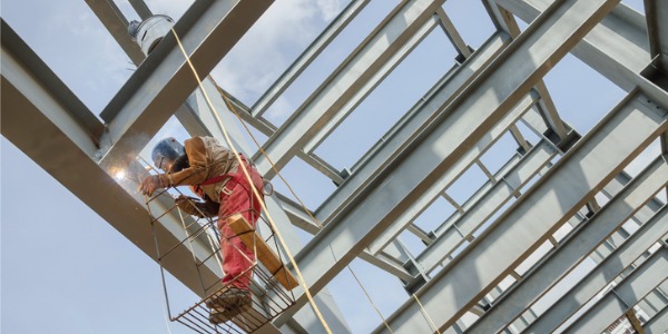 An ironworker welding a metal building structure.