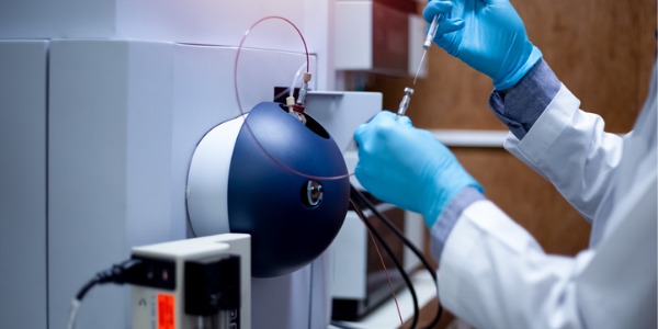 A nanosystems engineer injecting a sample with a micro syringe to TOF Mass Spectrometer for analysis.