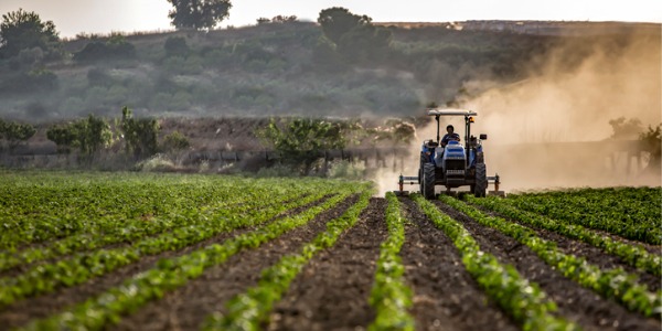 An agricultural worker riding a tractor.