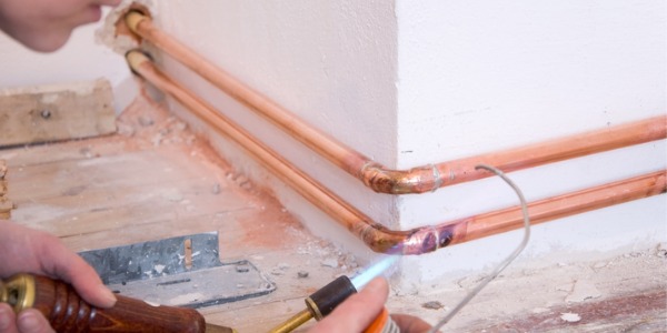 A pipefitter soldering copper pipes.