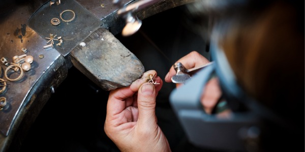 A precious metal worker creating a decorative gold piece of jewellry.