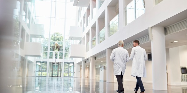Two doctors walking down a modern hospital hallway designed by a healthcare interior designer.