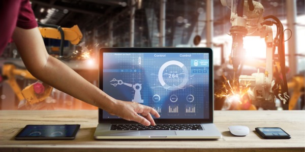 A control engineer using a laptop to check and control welding robotics automatic arms machine.