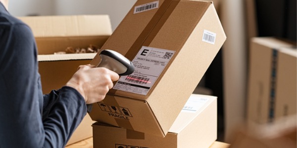 A postal service worker scanning barcodes on parcels.