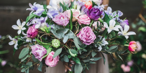 A bride holding a flower arrangement made by a wedding florist.