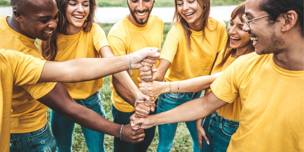 A youth group stacking hands outside in a circle, getting ready to do a recreational activity.