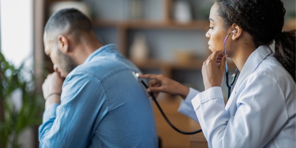 A respiratory therapist checking a patient's lungs with a stethoscope.