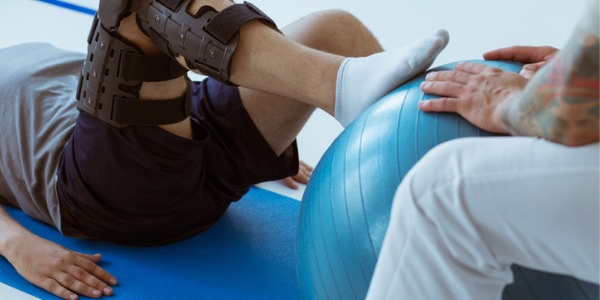 A rehabilitation trainer helping a client with a knee injury.